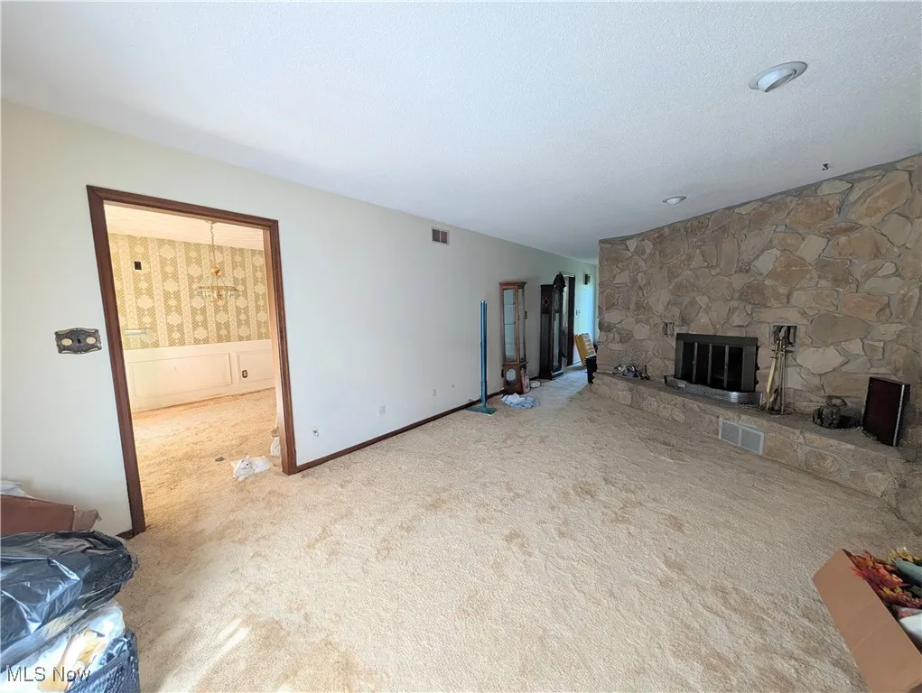 Unfurnished living room featuring carpet, a fireplace, and a textured ceiling
