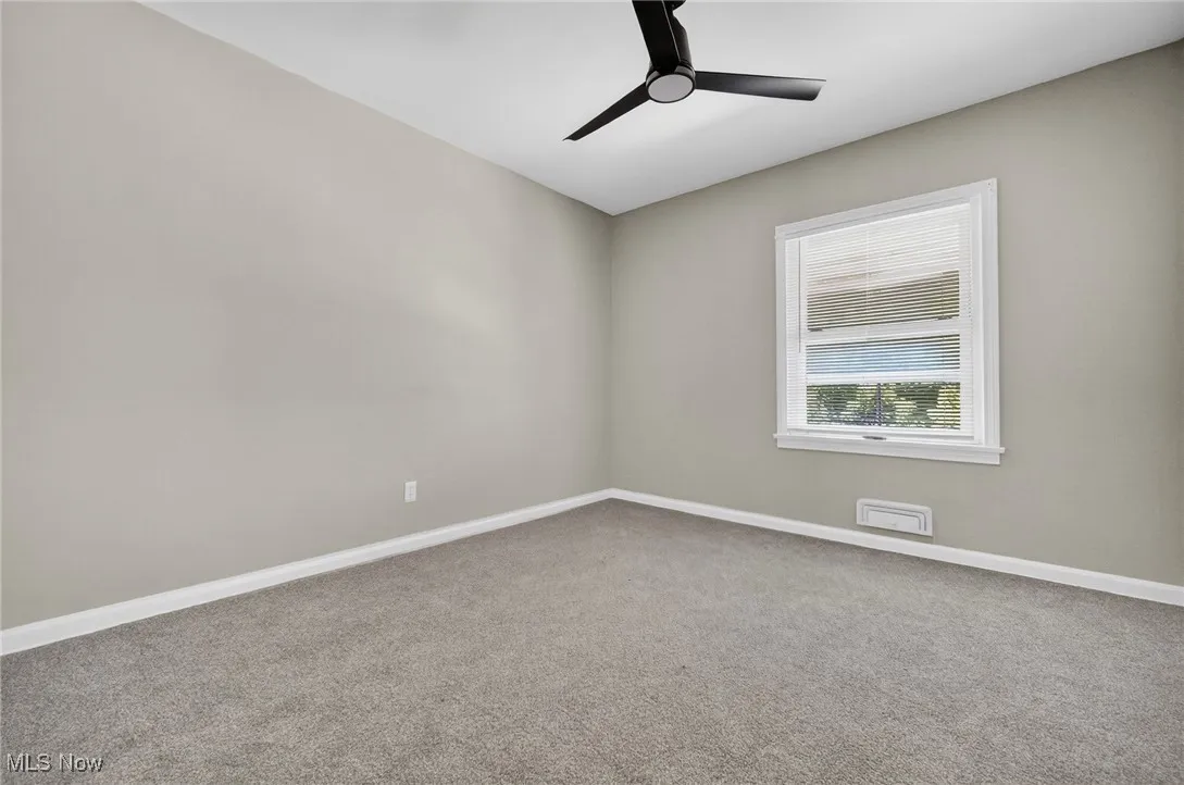 Carpeted spare room with a ceiling fan and baseboards