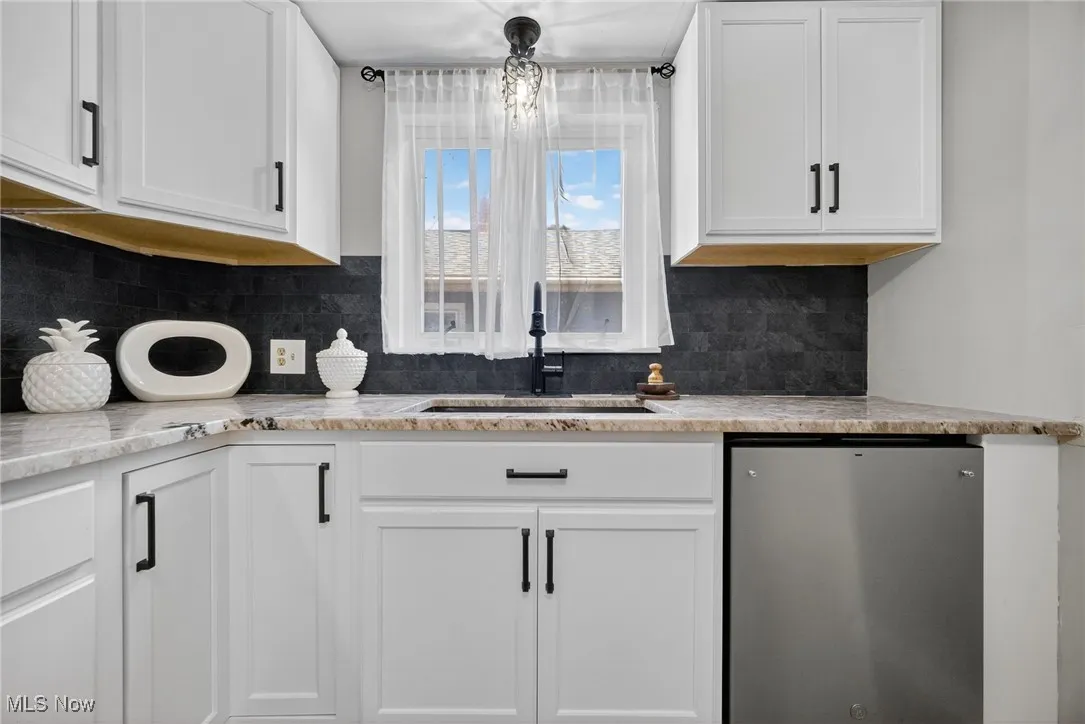 Kitchen with white cabinets, fridge, and decorative backsplash