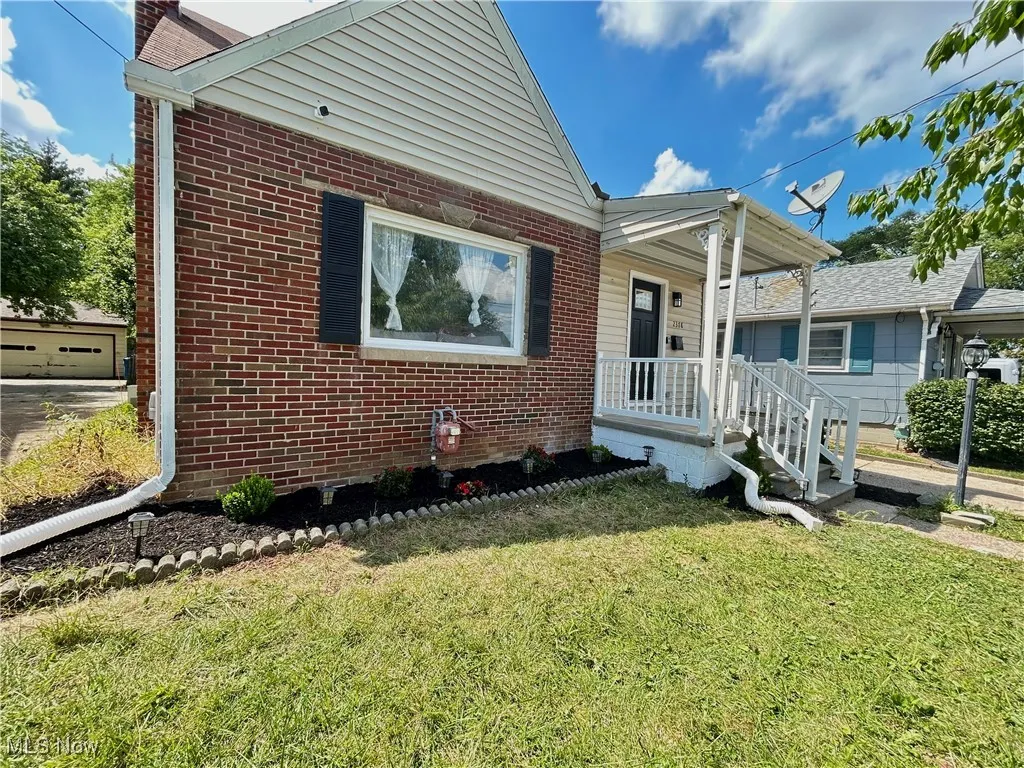 View of front of home featuring brick siding, a front lawn, and a garage