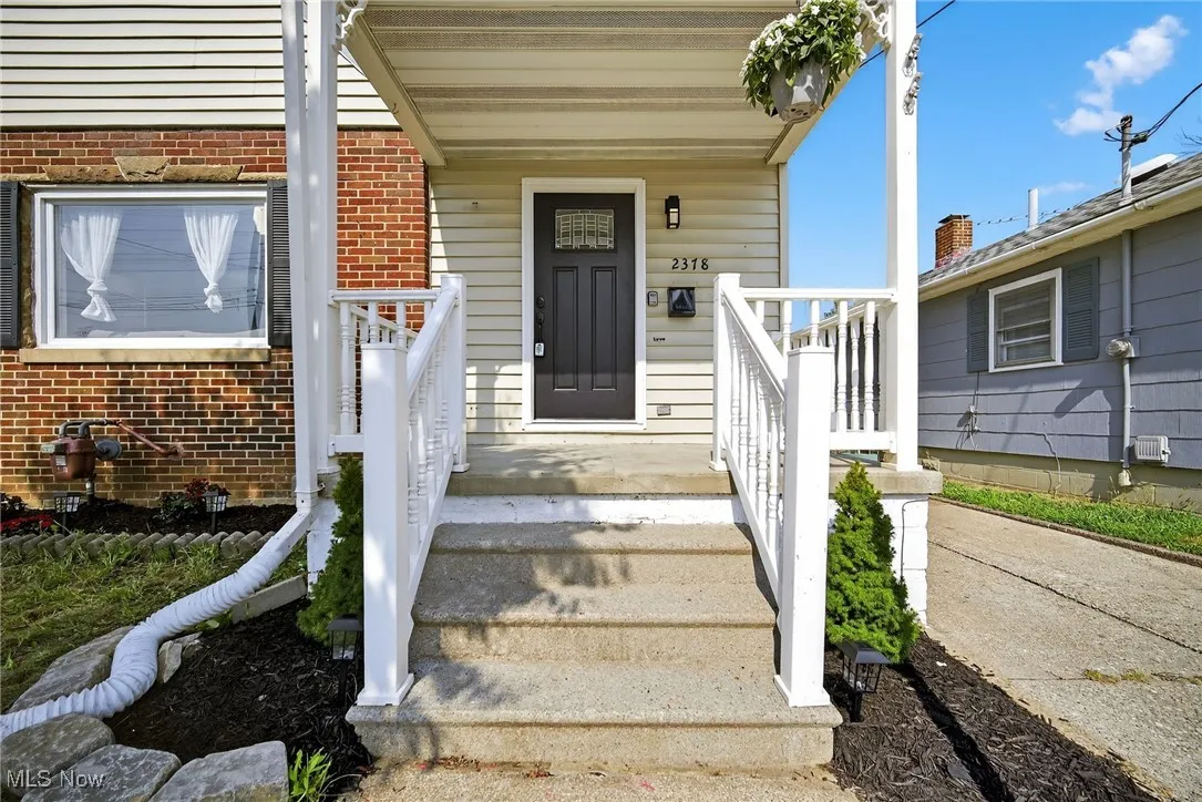 View of exterior entry featuring brick siding and covered porch