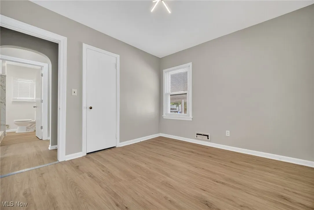 Unfurnished bedroom featuring light wood-style flooring and arched walkways