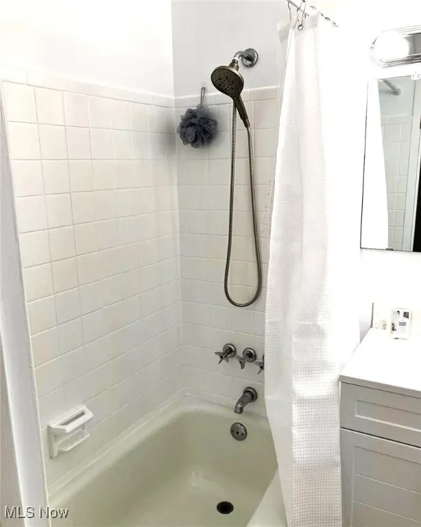 Full bath with shower / bath combination with curtain and vanity