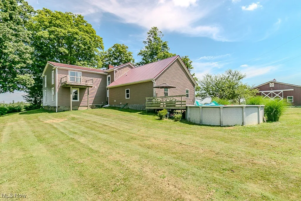 Back of property featuring a covered pool, a lawn, and a wooden deck