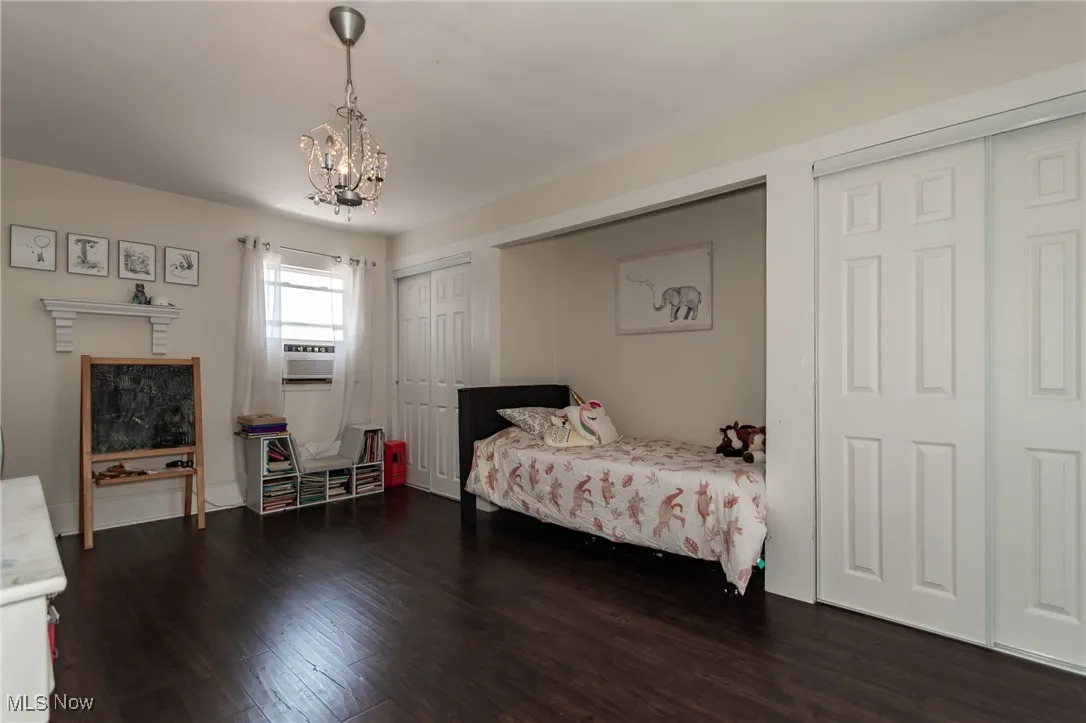Bedroom 3 with a chandelier, dark wood-type flooring, and multiple closets