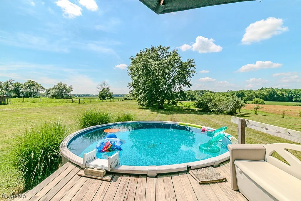 View of pool with a view of rural / pastoral area, a wooden deck, and a lawn