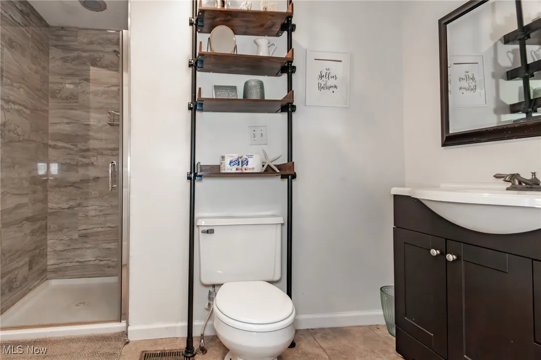 Bathroom with a shower stall, vanity, and tile patterned flooring