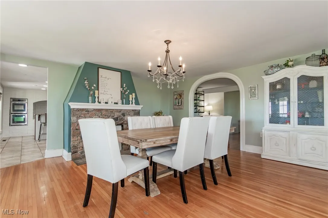 Dining area with arched walkways, a chandelier, and light wood finished floors