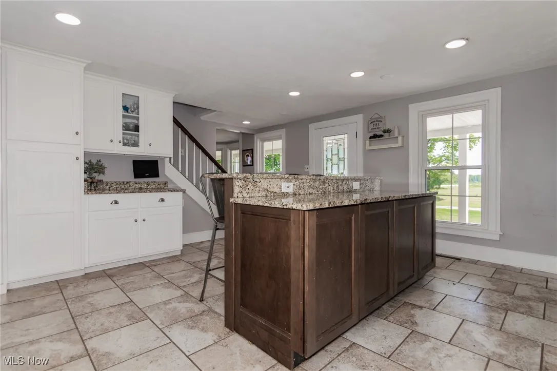 Kitchen with recessed lighting, healthy amount of natural light, white cabinetry, and light stone countertops