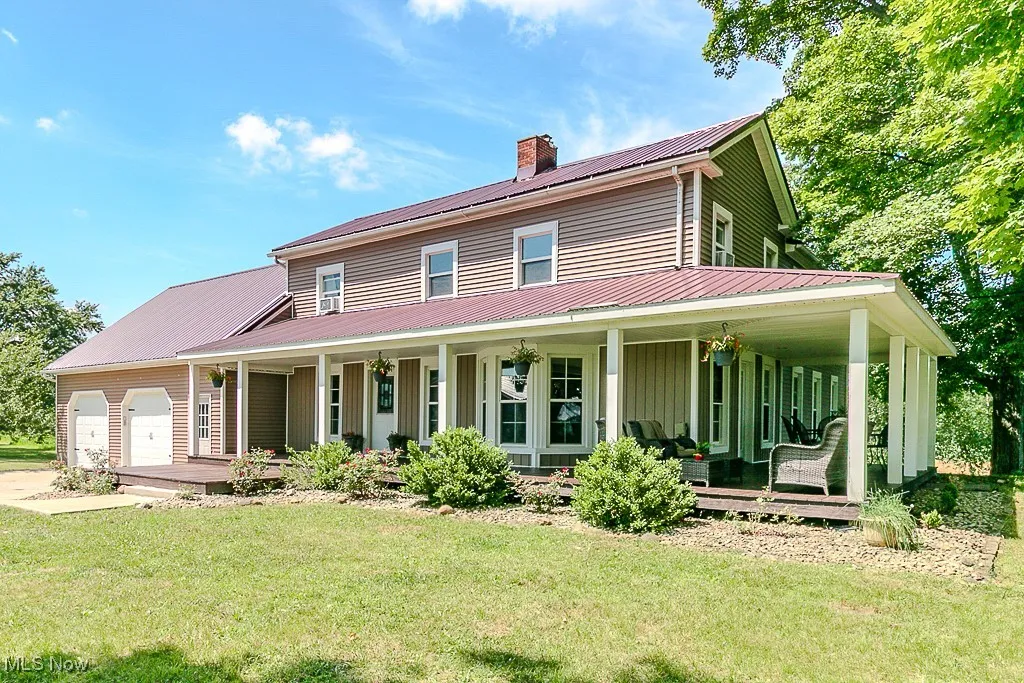 View of front facade with a porch, a metal roof, a chimney, a front yard, and an attached garage