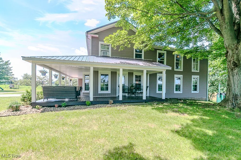 Farmhouse-style home featuring a front lawn, covered porch, and a metal roof