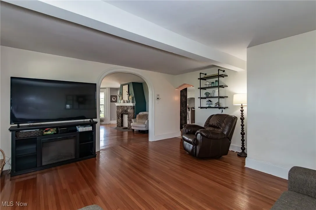 Living room featuring arched walkways, a fireplace, and wood finished floors