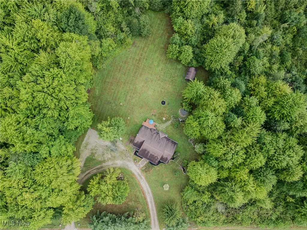 Aerial view of property and surrounding area featuring a forest