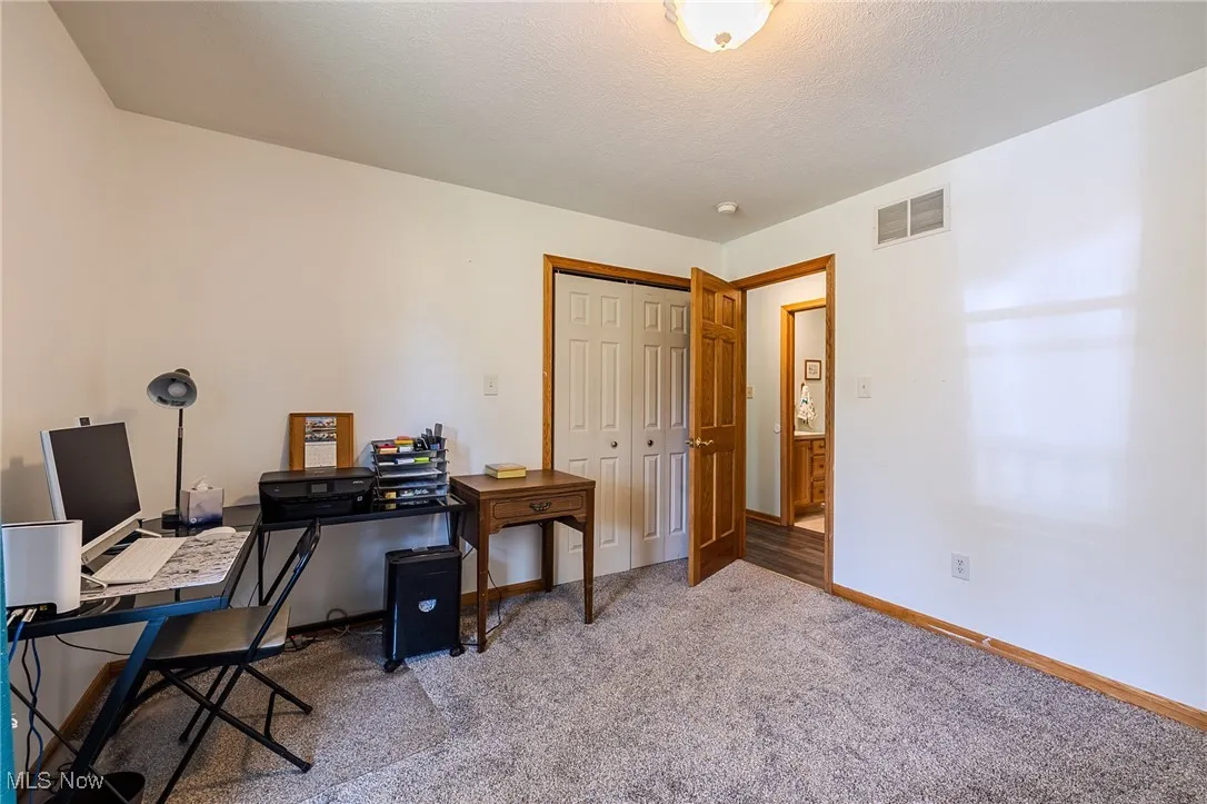 Bedroom currently being used as an office featuring carpet and a textured ceiling