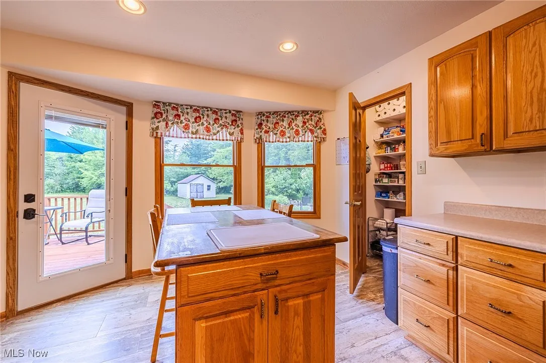 Kitchen with brown cabinets, light wood finished floors, a center island, and recessed lighting