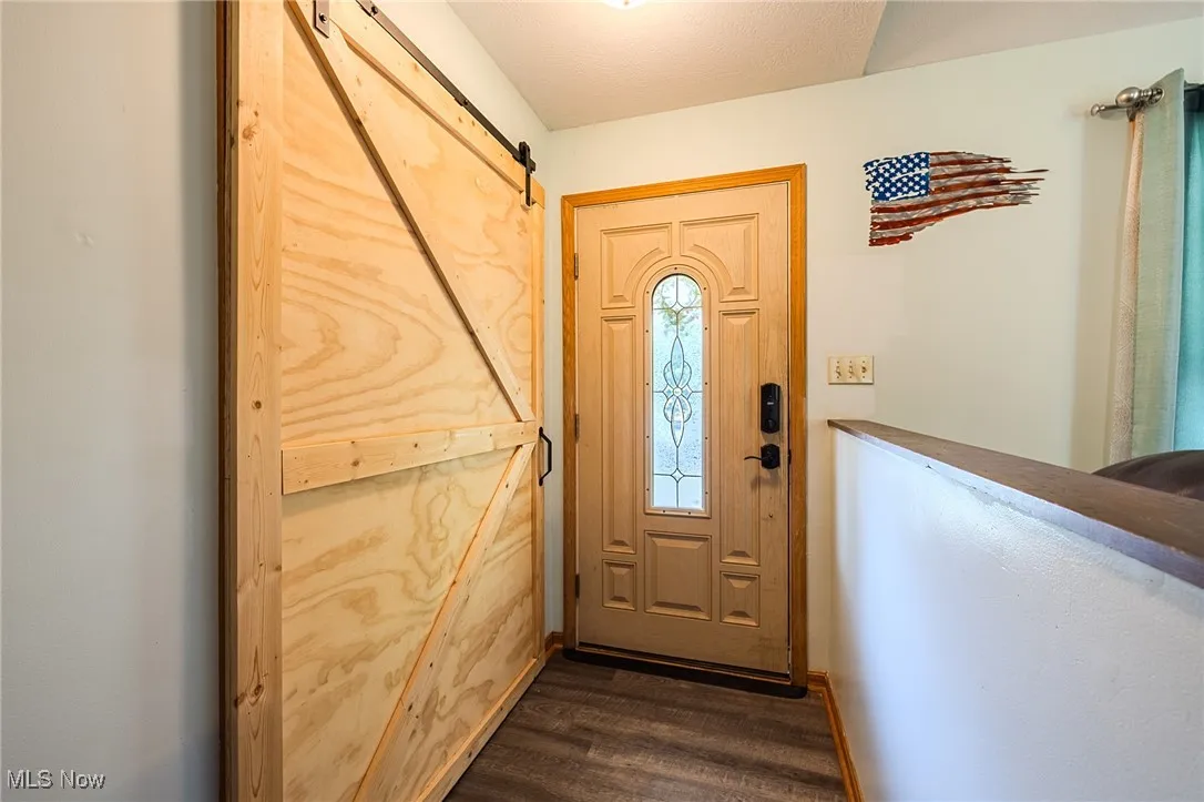 Doorway with a barn door and dark wood-type flooring