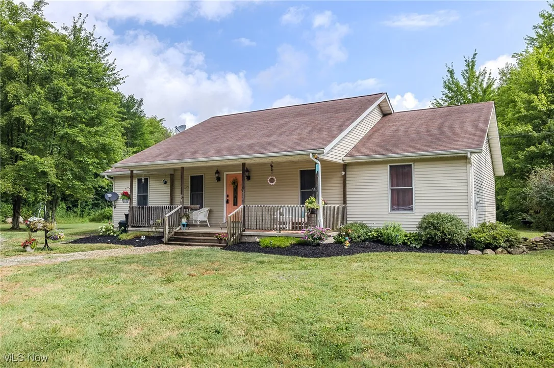 View of front of property featuring covered porch, a front lawn, and roof with shingles