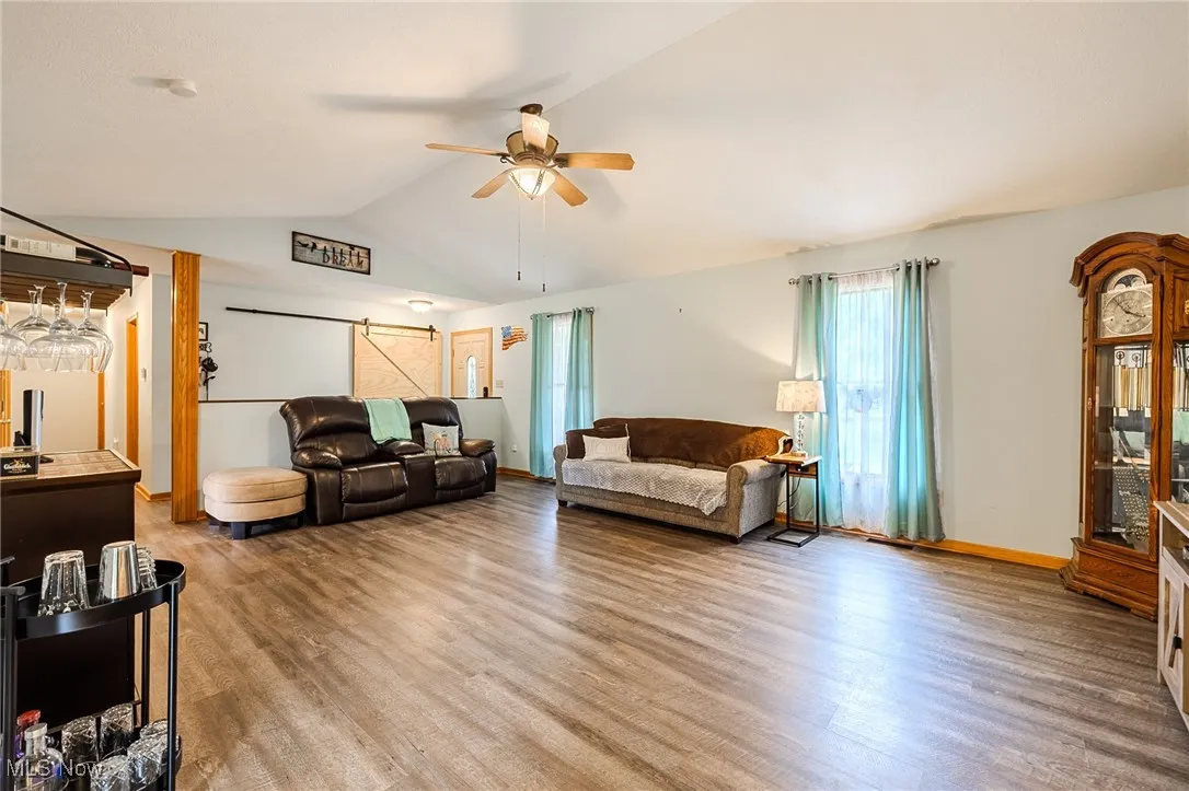 Living area featuring wood finished floors, vaulted ceiling, and ceiling fan