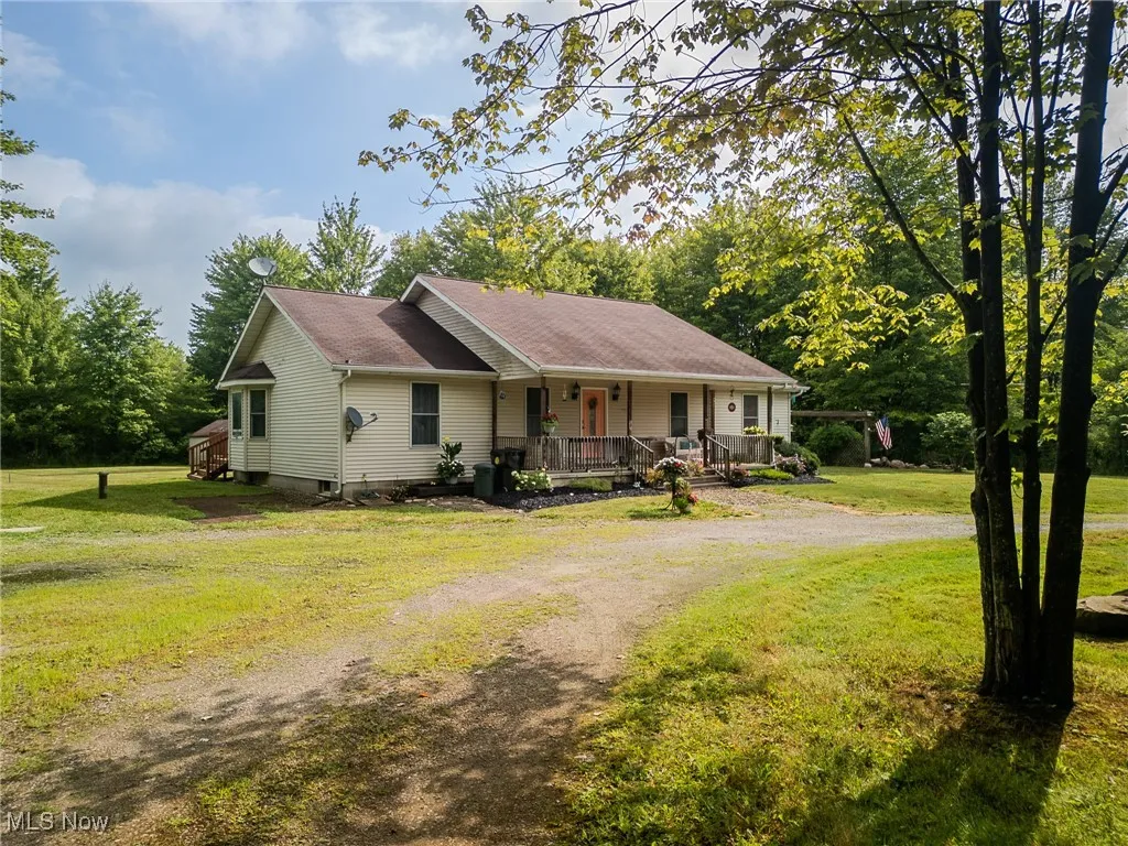 Ranch-style house featuring covered porch, dirt driveway, a front yard, and roof with shingles