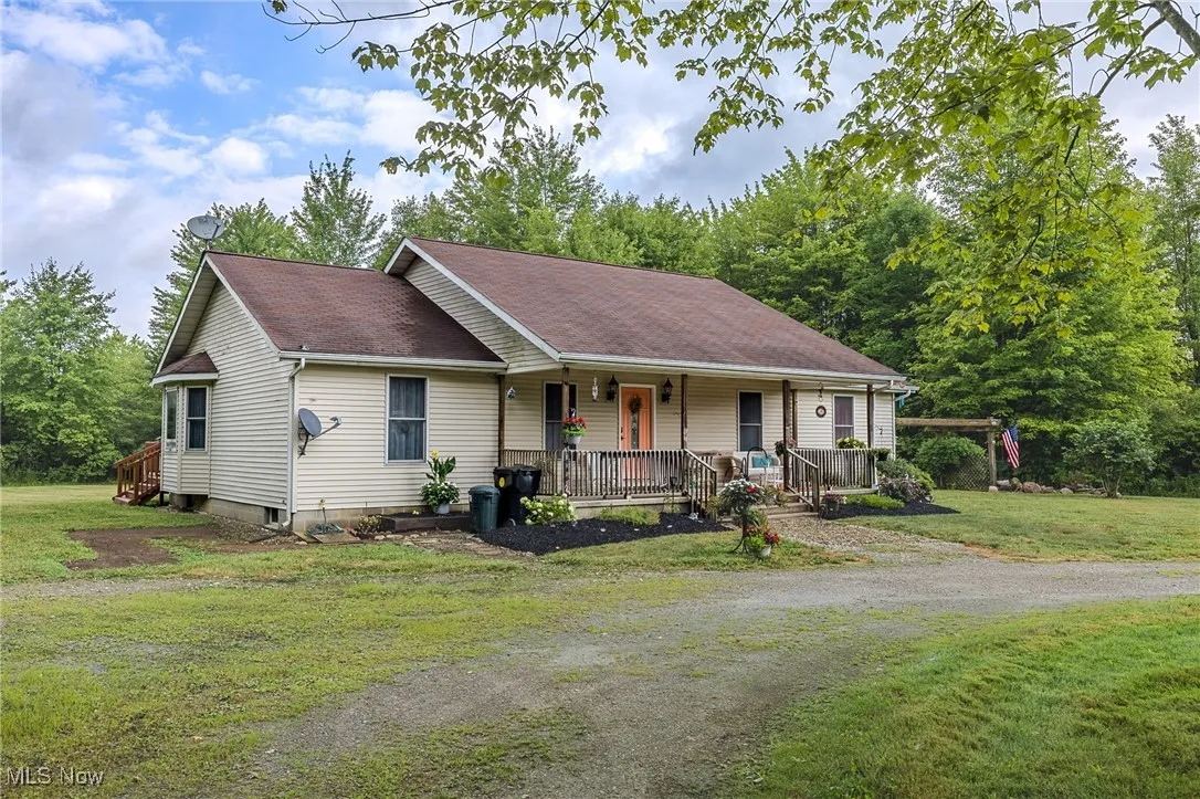 Ranch-style house featuring covered porch, a front yard, and a shingled roof