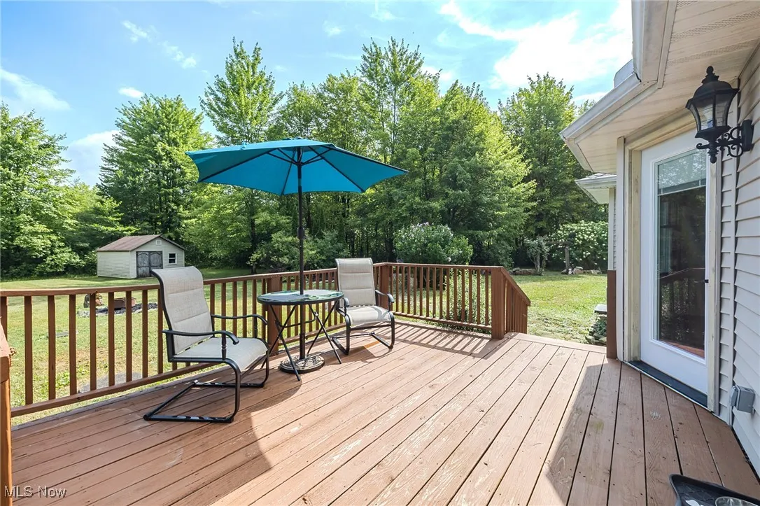 Wooden terrace featuring a storage shed, a lawn, and view of scattered trees