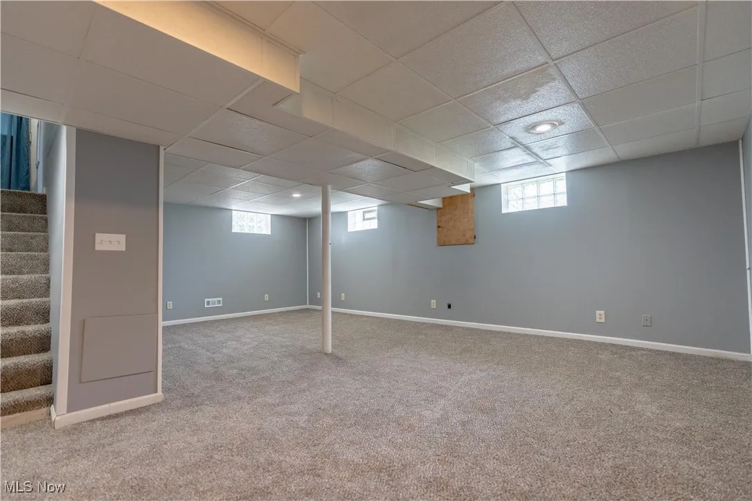 Below grade area featuring a paneled ceiling, stairway, carpet, and recessed lighting
