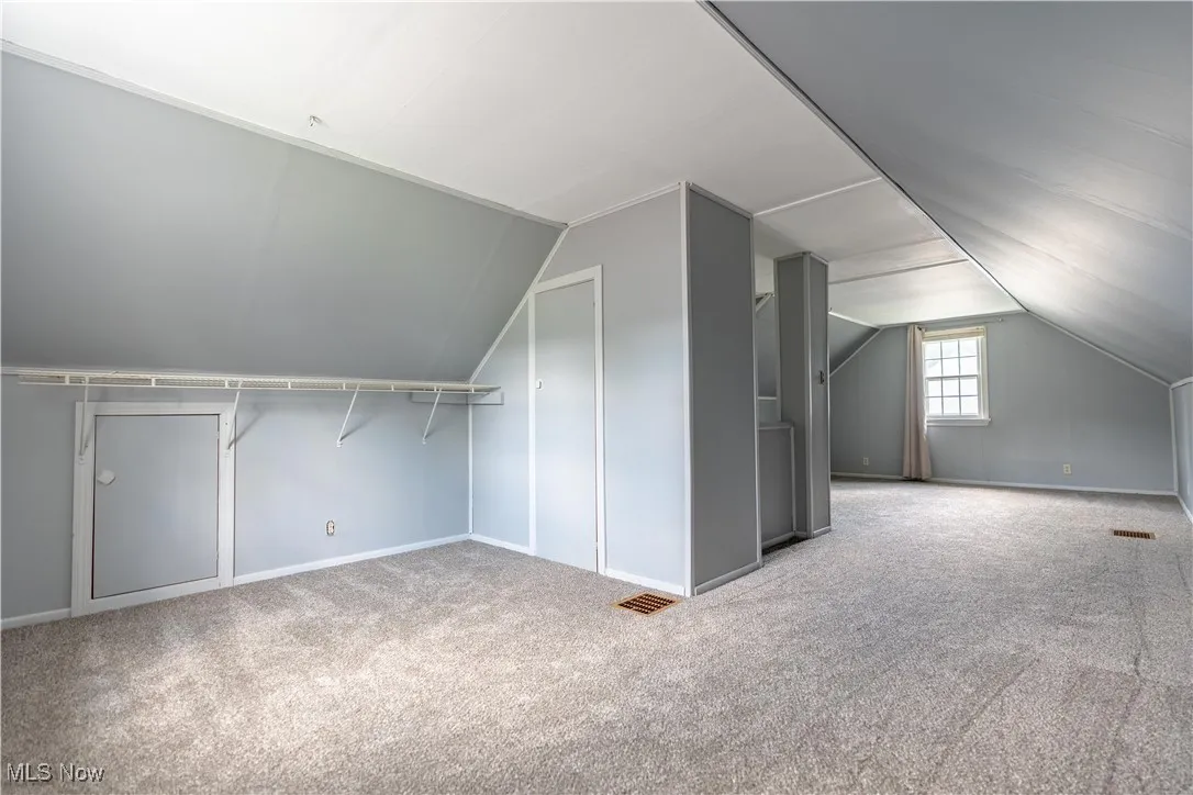 Bonus room with carpet flooring and vaulted ceiling