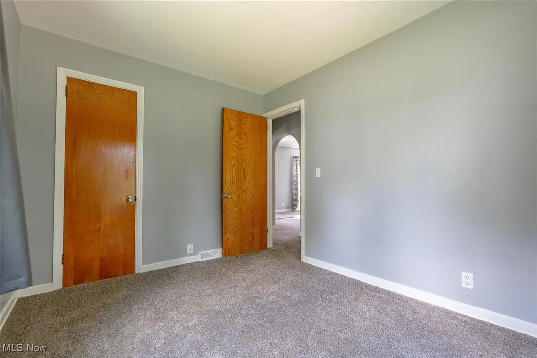 Unfurnished bedroom featuring carpet flooring and arched walkways