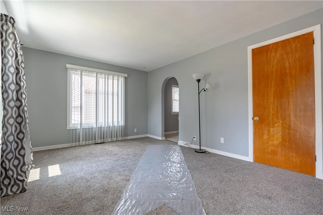 Carpeted empty room with arched walkways and baseboards