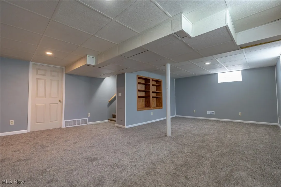 Basement with a paneled ceiling, carpet floors, stairs, and recessed lighting