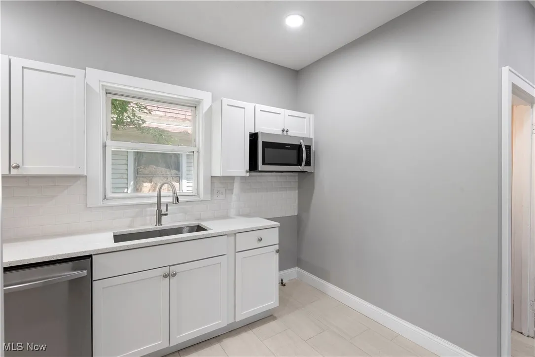 Kitchen featuring appliances with stainless steel finishes, light countertops, and white cabinetry