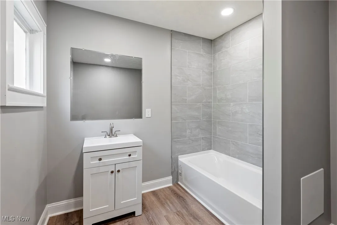Bathroom featuring wood finished floors, vanity, recessed lighting, and shower / bath combination