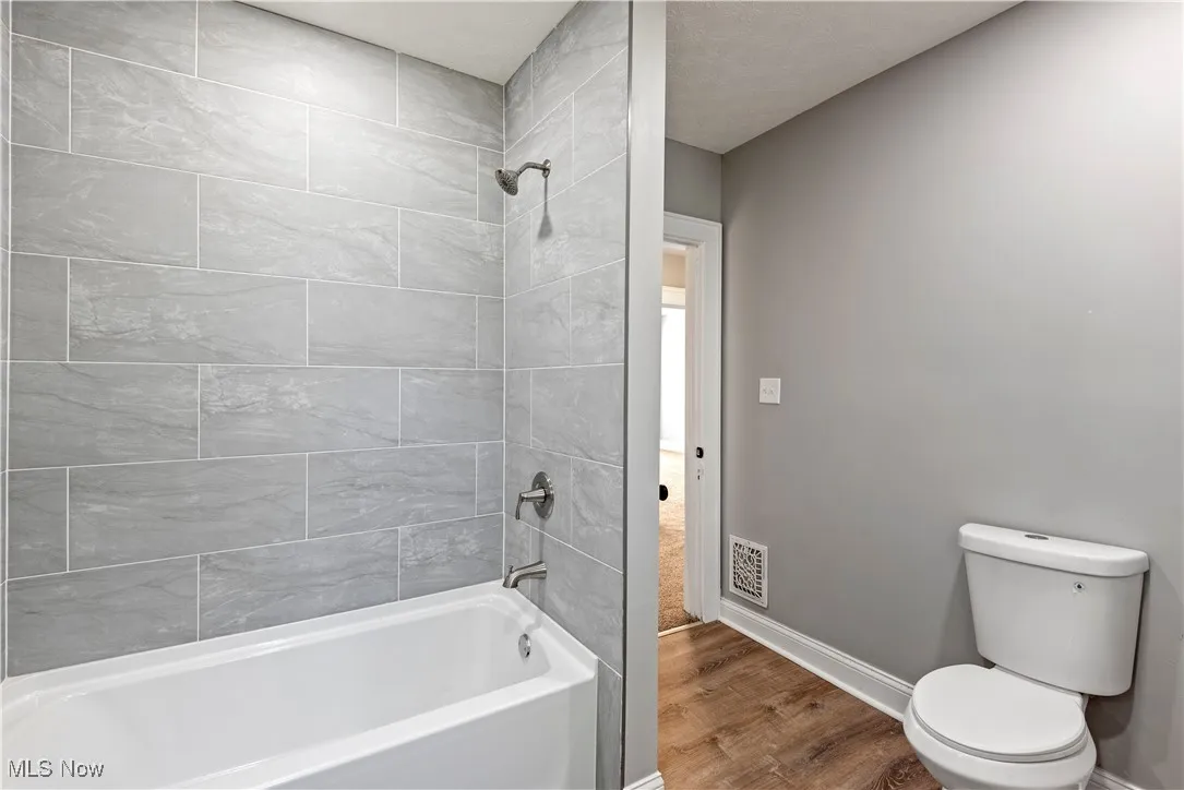 Full bathroom with wood finished floors and shower / bath combination