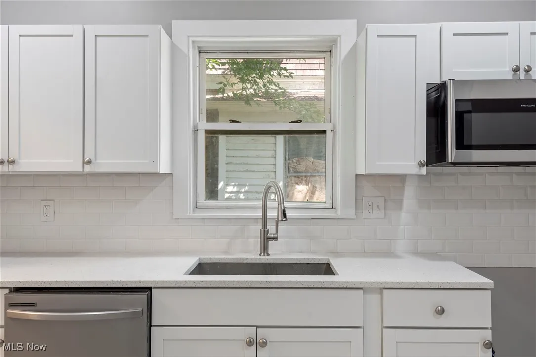 Kitchen with appliances with stainless steel finishes, white cabinetry, and backsplash