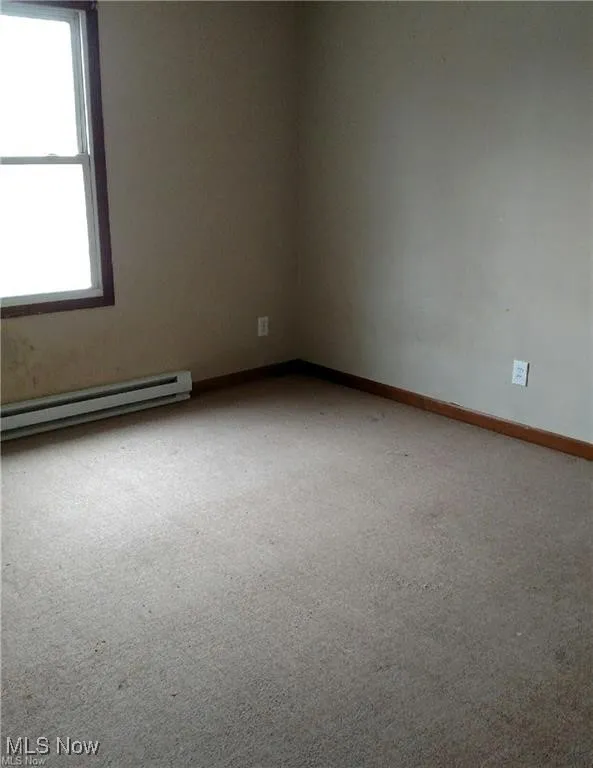 Spare room featuring baseboard heating and carpet flooring