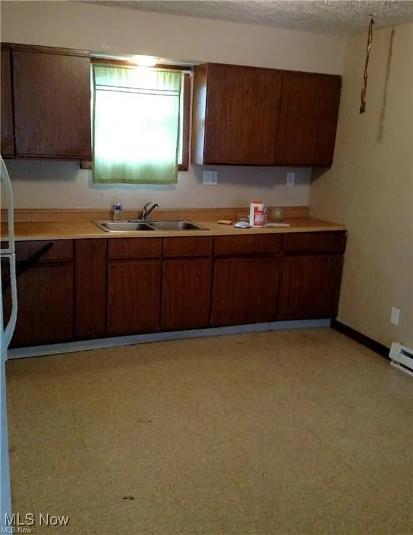 Kitchen featuring light floors, light countertops, a textured ceiling, and a baseboard radiator