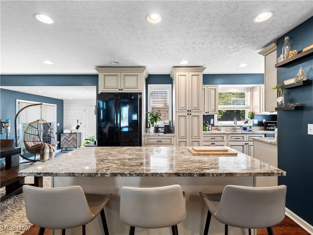 Kitchen featuring hardwood flooring, granite counters, cream colored cabinets, and huge island