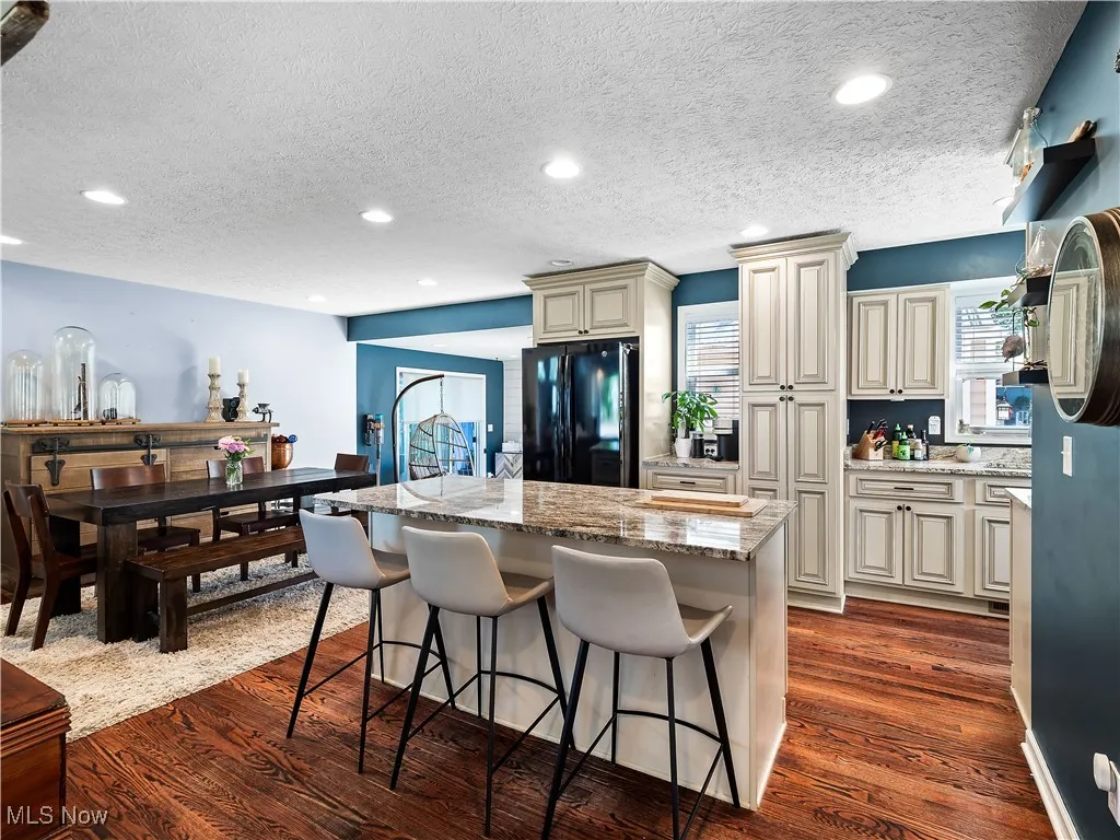 Kitchen featuring hardwood flooring, granite counters, cream colored cabinets, and huge island