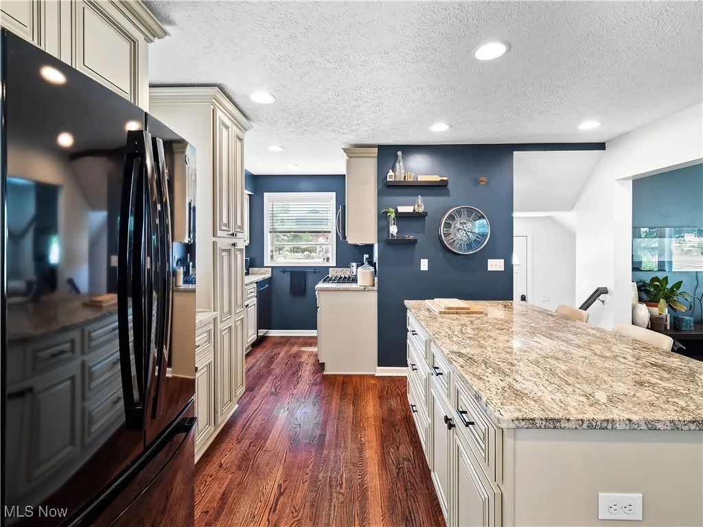 KKitchen featuring hardwood flooring, granite counters, cream colored cabinets, and huge island