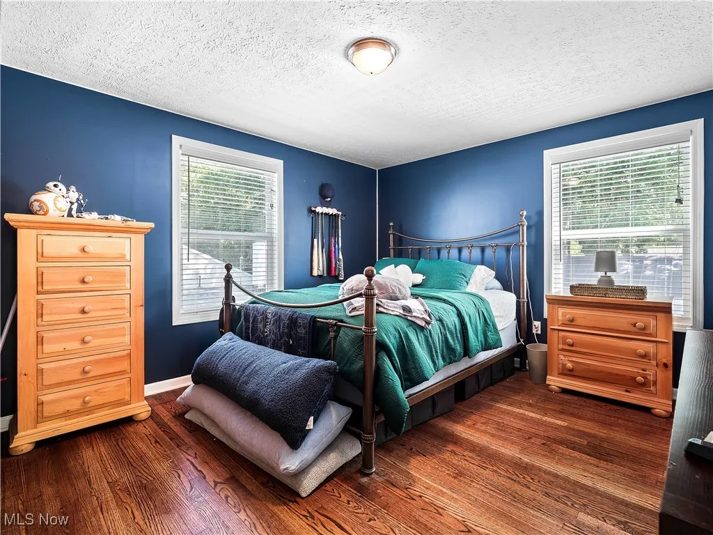 Bedroom with multiple windows and hardwood floors