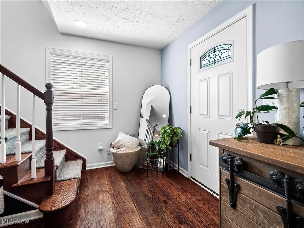 Foyer featuring stairway, dark wood floors and open to family room