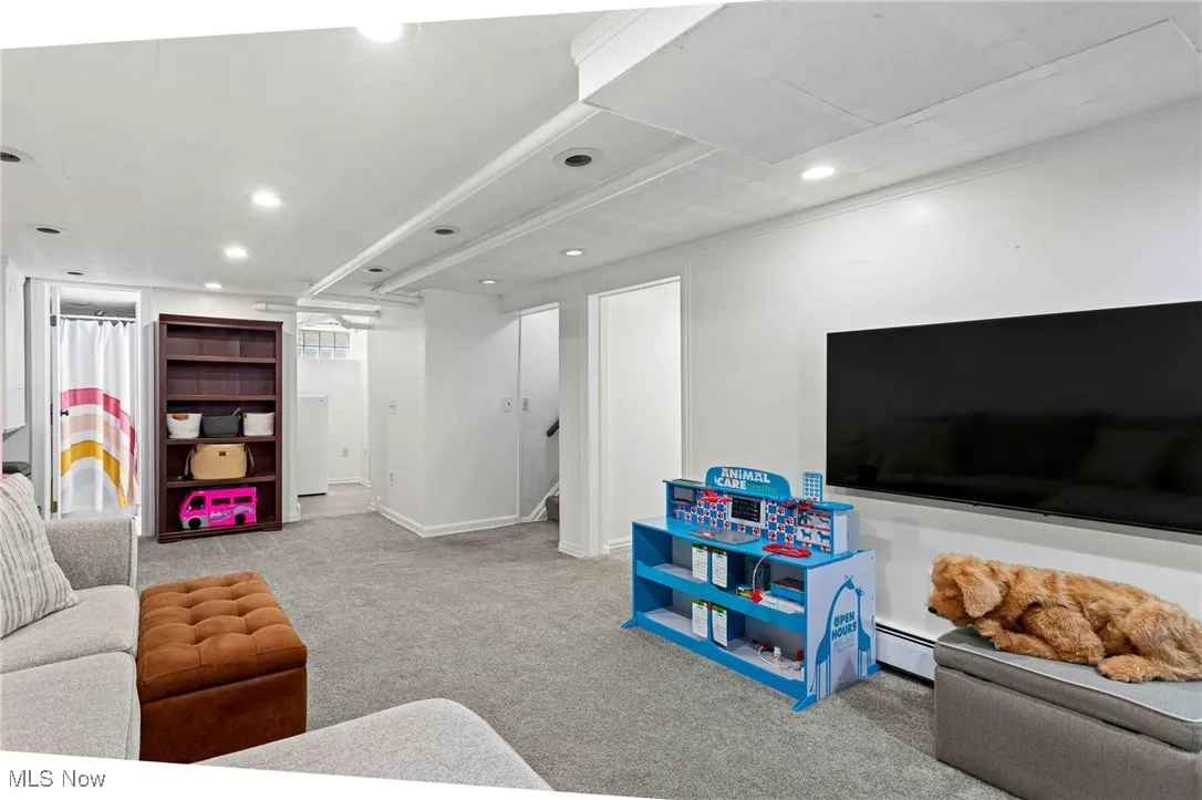 Living room with carpet floors, recessed lighting, baseboard heating, and crown molding