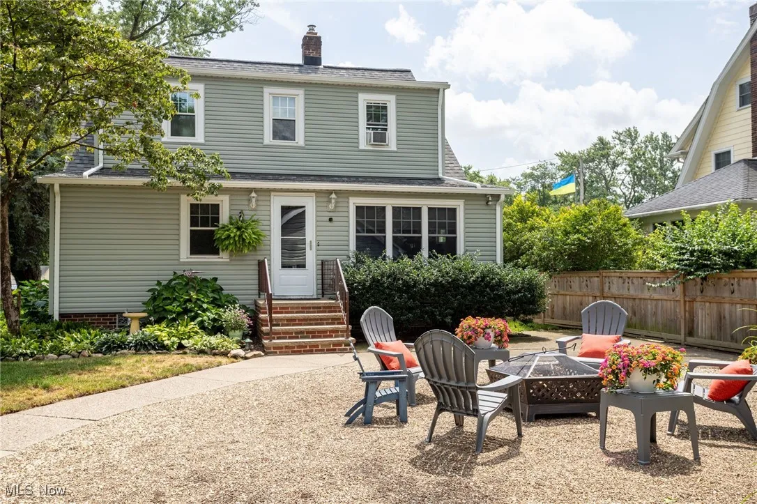Rear view of property featuring entry steps, a shingled roof, a chimney, and an outdoor fire pit