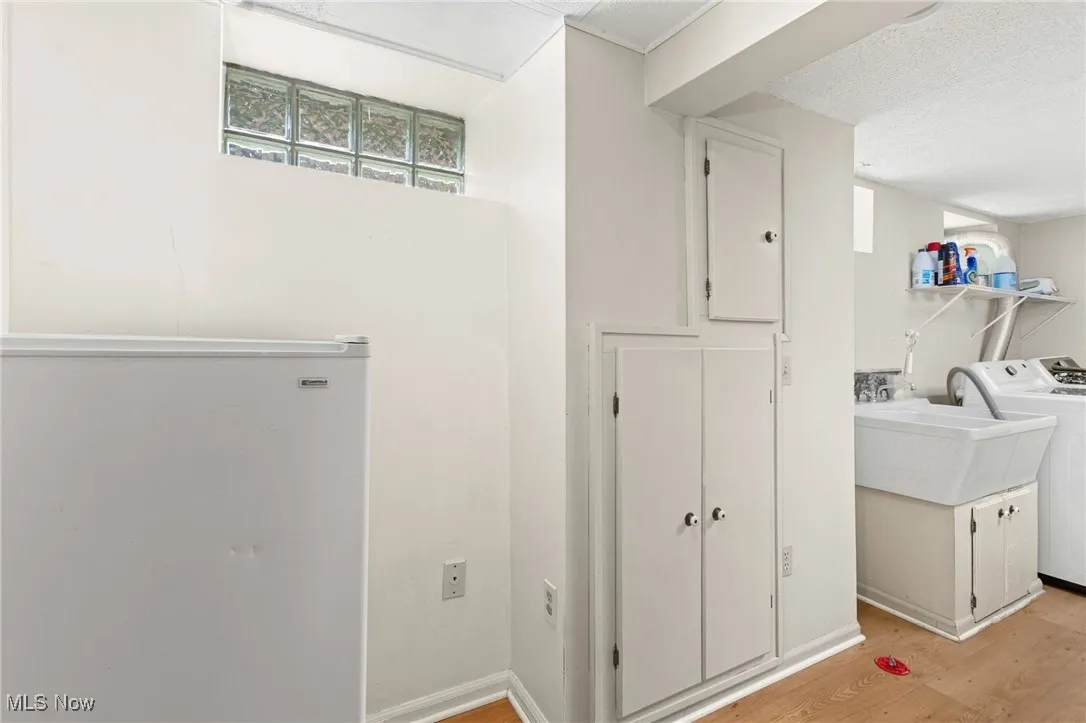 Laundry room with washer / dryer, light wood finished floors, healthy amount of natural light, and a textured ceiling