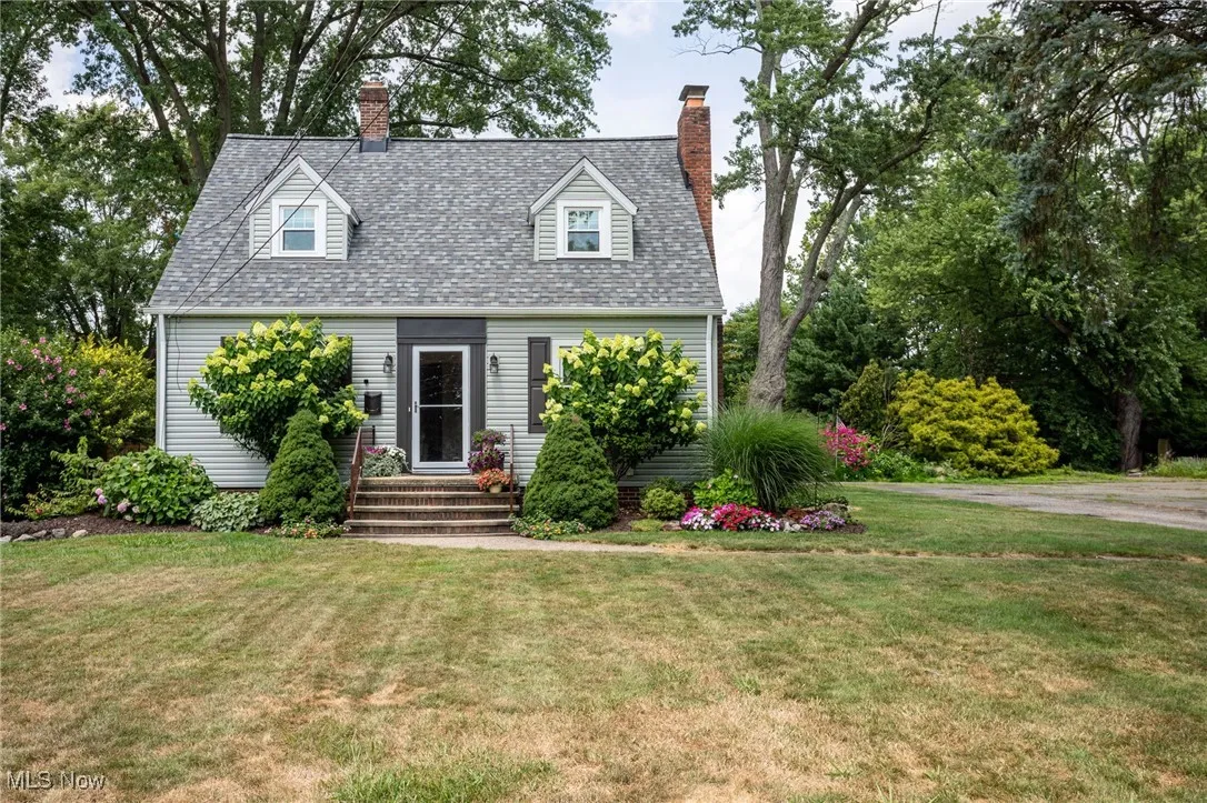 Cape cod house featuring a chimney, a front yard, and roof with shingles