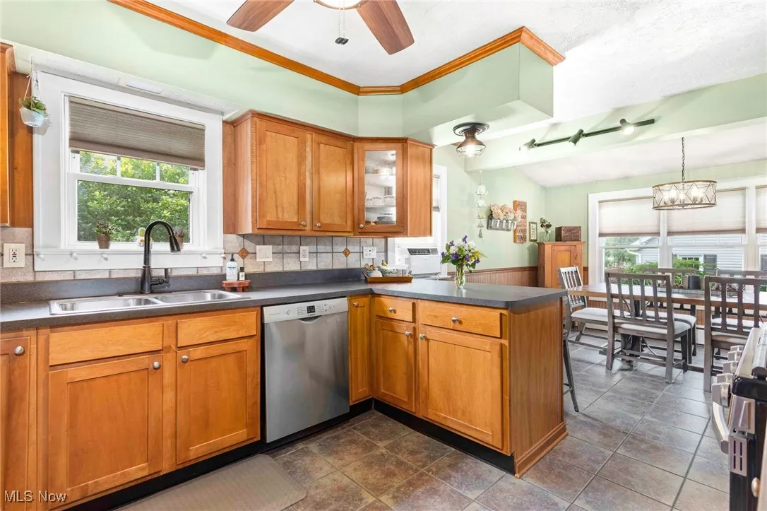 Kitchen with healthy amount of natural light, brown cabinets, a peninsula, appliances with stainless steel finishes, and vaulted ceiling