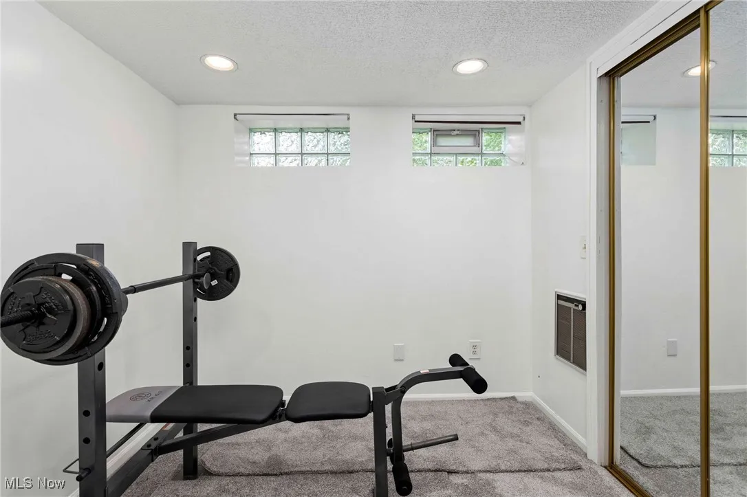 Exercise area featuring a textured ceiling, carpet, recessed lighting, and heating unit