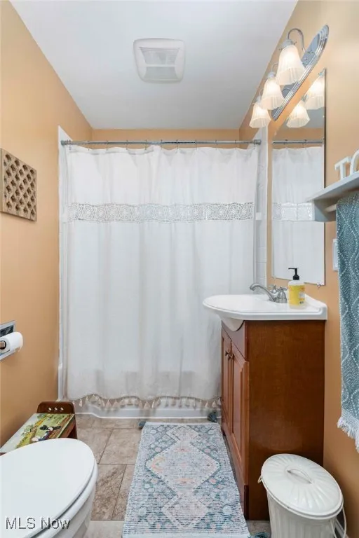 Full bath with vanity, tile patterned floors, and curtained shower