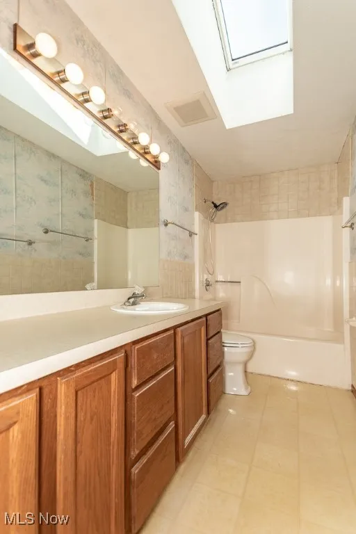 Full bath with a skylight, vanity, wallpapered walls, and  shower combination