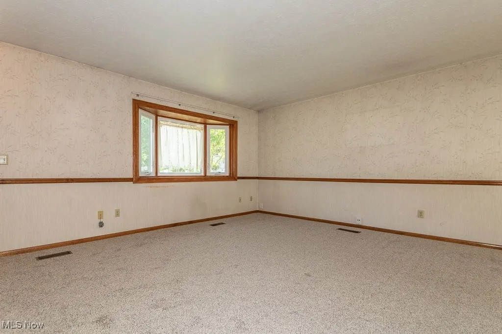 Living room with wallpapered walls and a textured ceiling